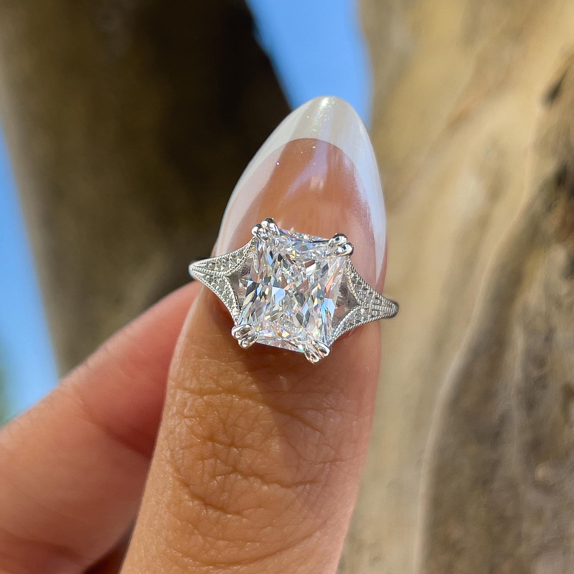 bold 3 carat radiant cut vintage engagement ring on a model with french tip nails 
