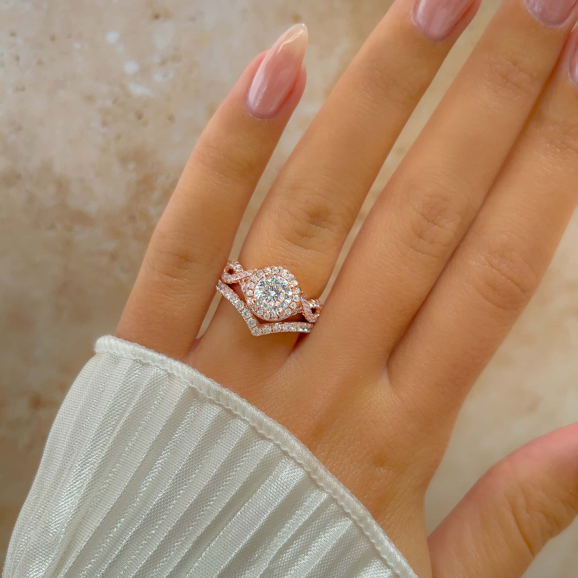 stunning rose gold round cut twisted engagement ring with chevron wedding band on model's finger