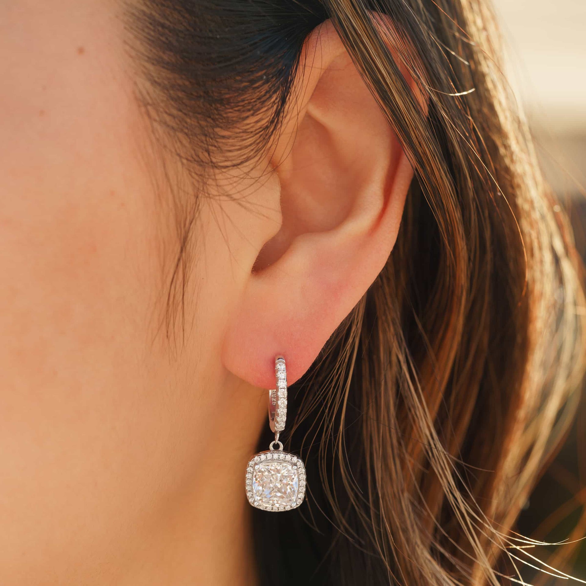 stunning silver cushion cut earring on model's ear