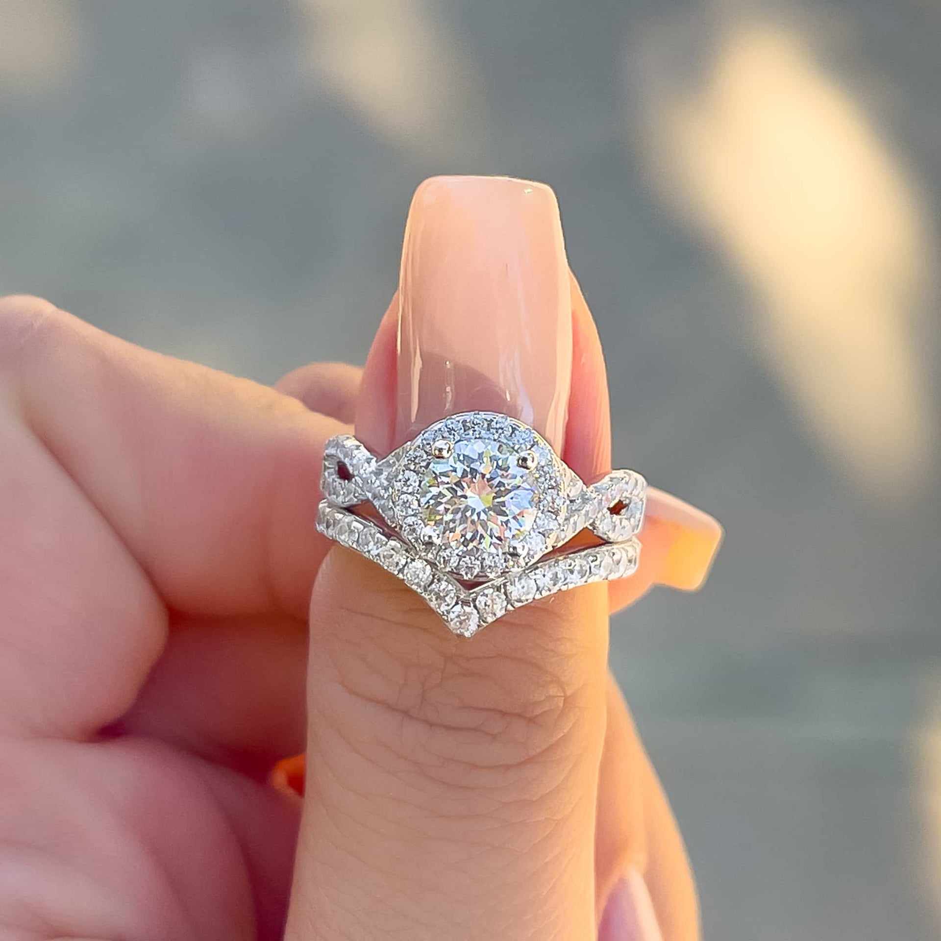 vintage round cut halo engagement ring paired with chevron zoey wedding band on model with neutral nails