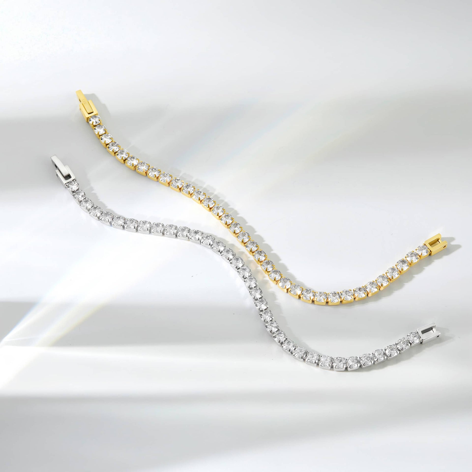 shot of two gorgeous tennis bracelets unclasped in a natural position shown in gold and silver on a white background