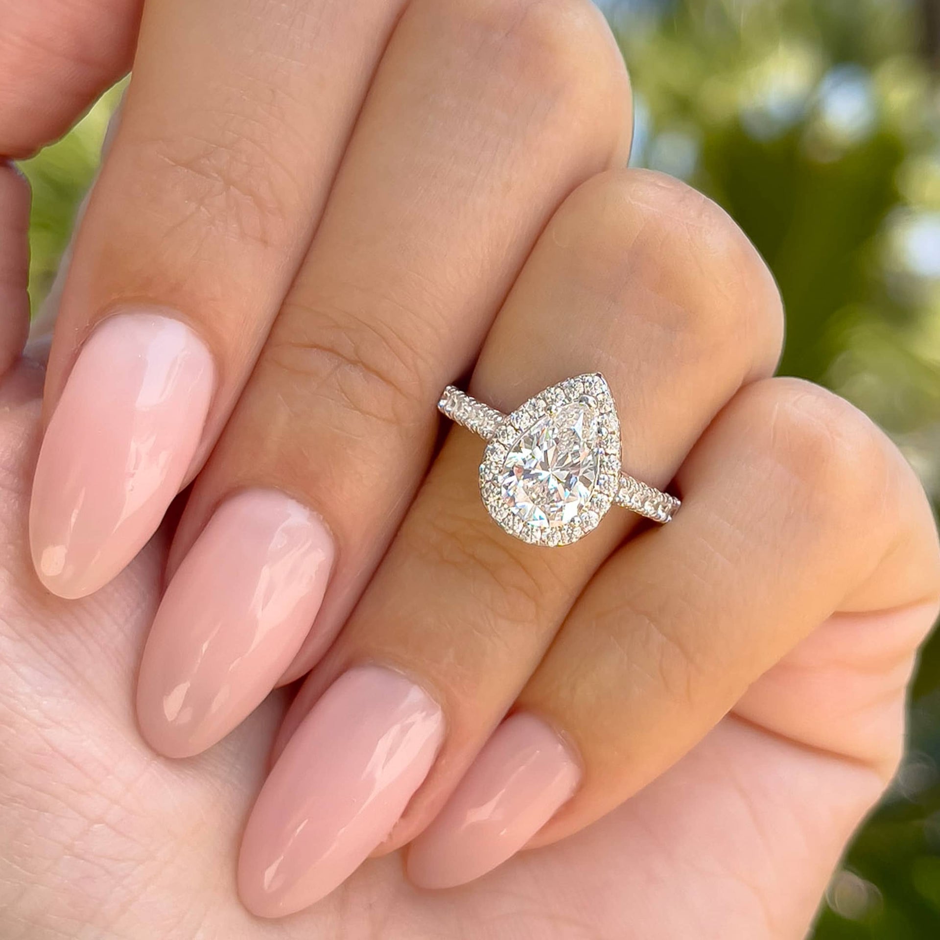 gorgeous pear cut engagement ring shown on ladies hand with pink nails