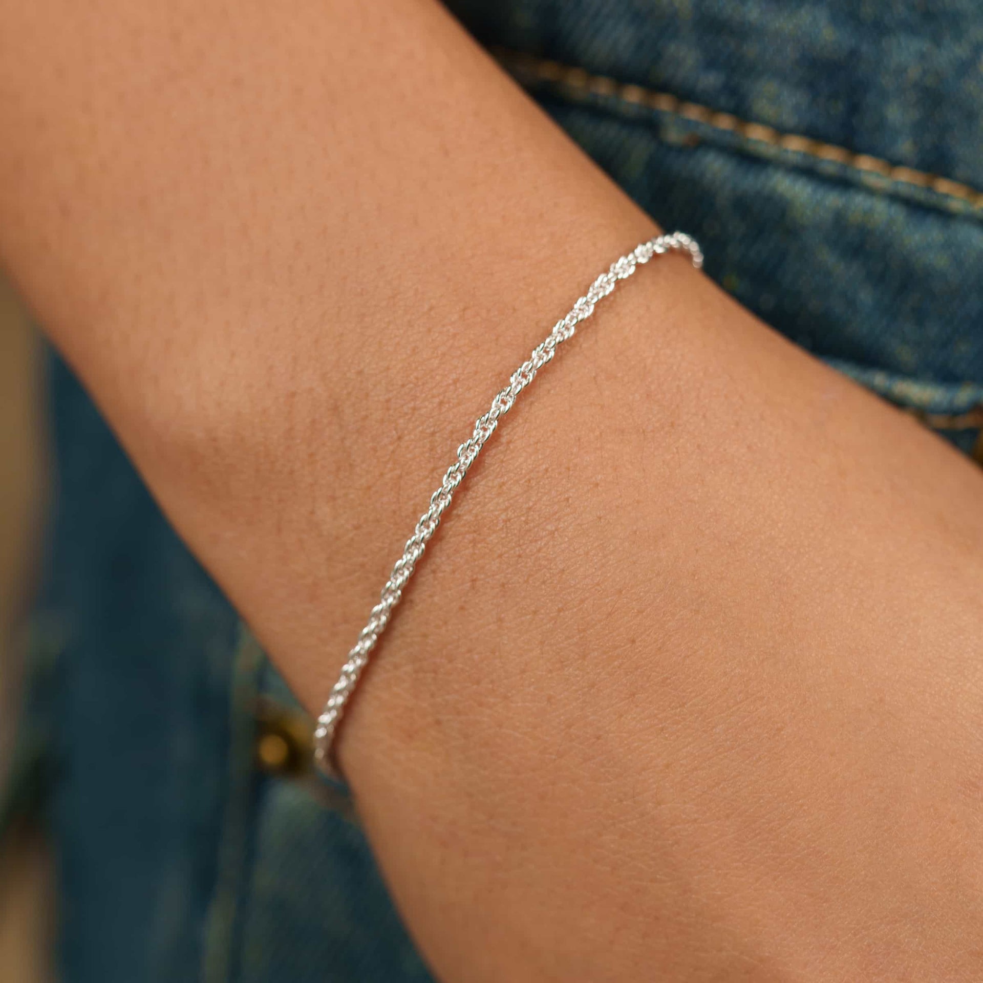 a silver rope style bracelet on model wearing denim