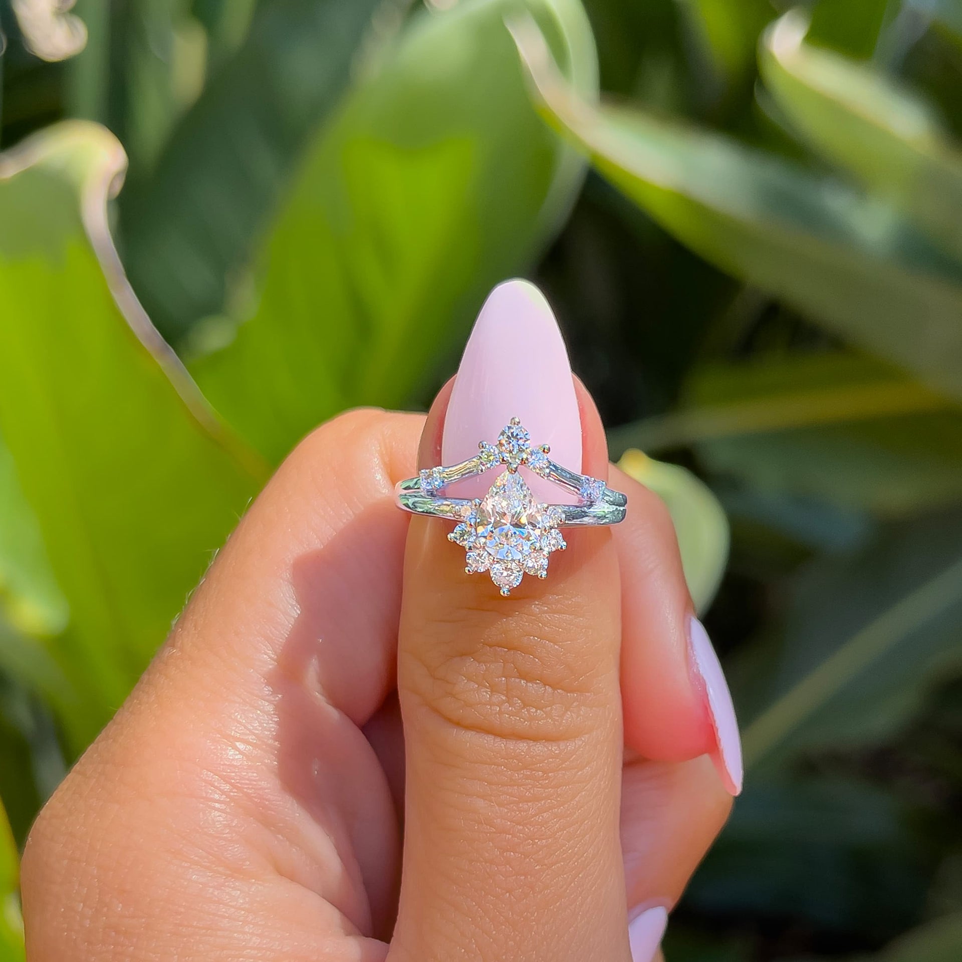 stunning silver boho pear cut engagement ring held by model with light pink nails