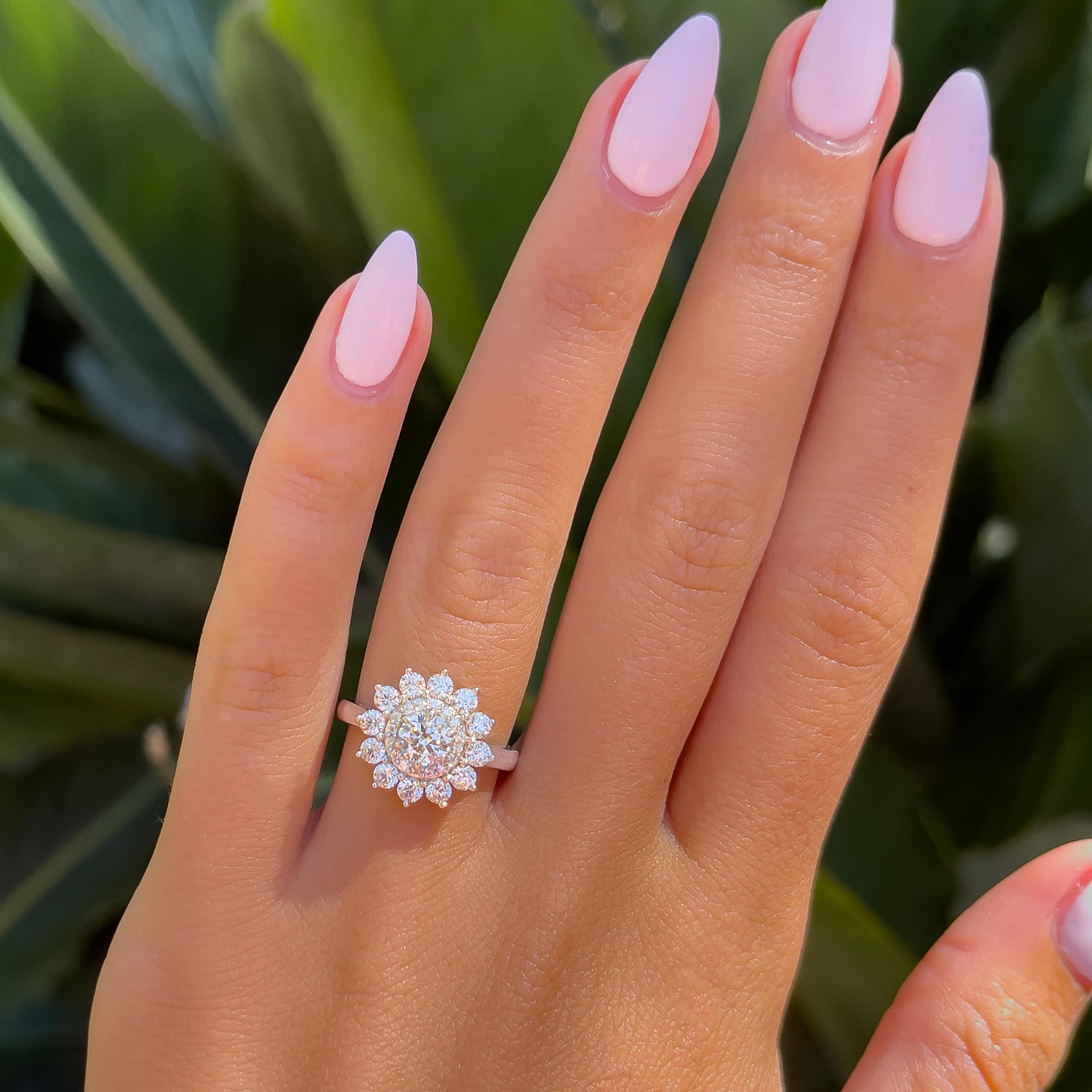 unique silver flower shaped engagement ring on model with light pink nails