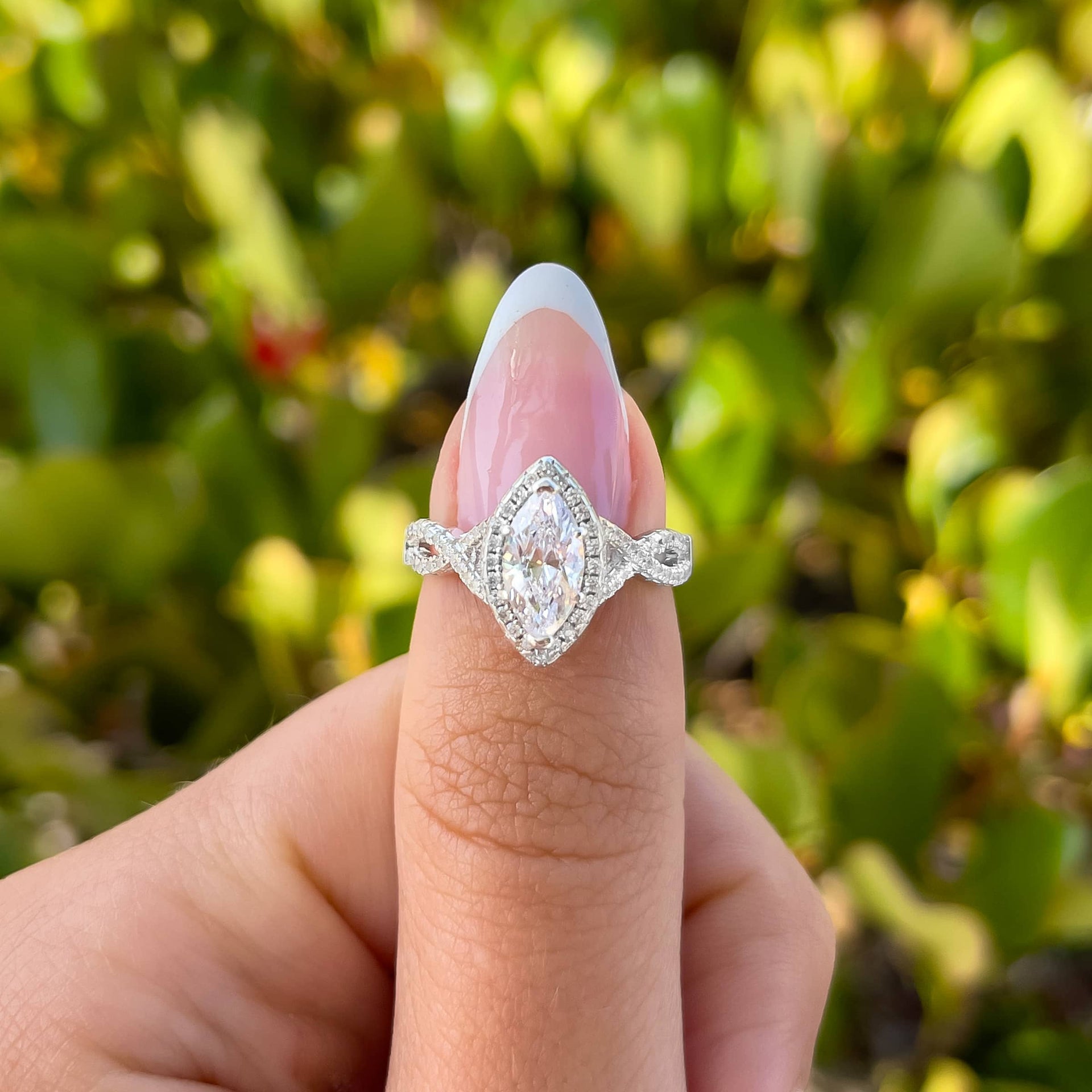 vintage marquise cut engagement ring with halo and twisting detail on model with french tip nails