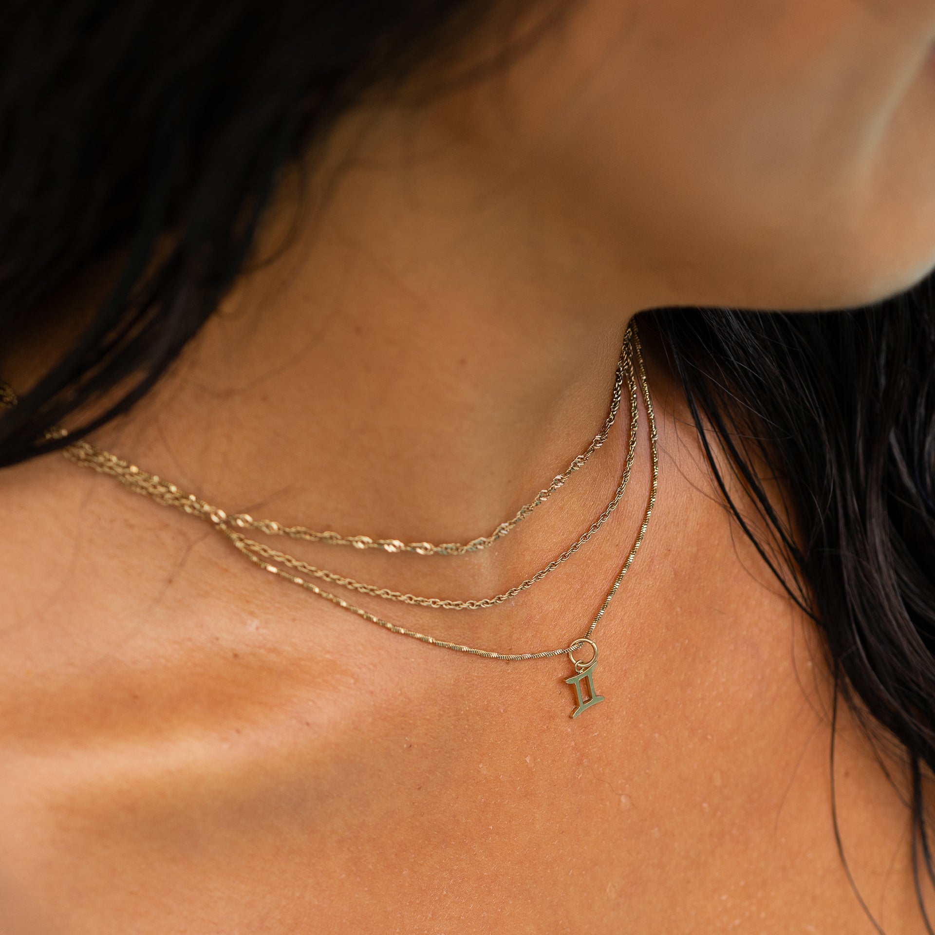a layered 14k gold PVD plated stainless steel necklace look complete with a dainty zodiac charm worn by model with dark hair