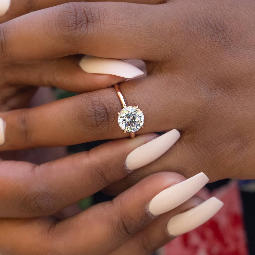 lady putting on solitaire engagement ring