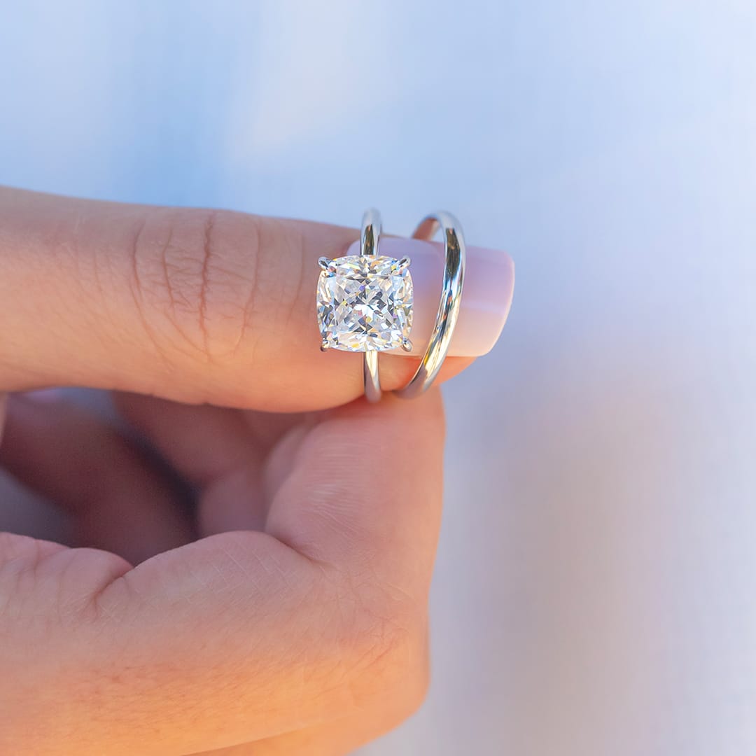 finger holding solitaire rings